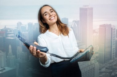 Bir sabit hat telefonu tutan memnun güzel kadın