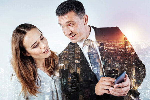 Friendly man showing a new smart phone to his pretty colleague