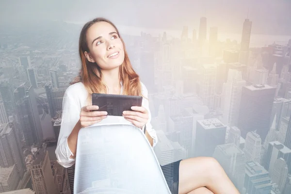 Femme rêveuse avec un gadget assis sur une chaise blanche — Photo