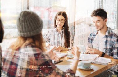 Dinlenmek. Pozitif akıllı öğrenciler masada otururken ve iletişim kurarken kafede vakit geçirirler