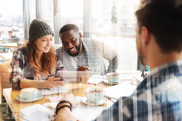 Heyecan verici bir video. Gülümseyen konsantre arkadaşlar heyecanla ekrana bakarken tablet tutan