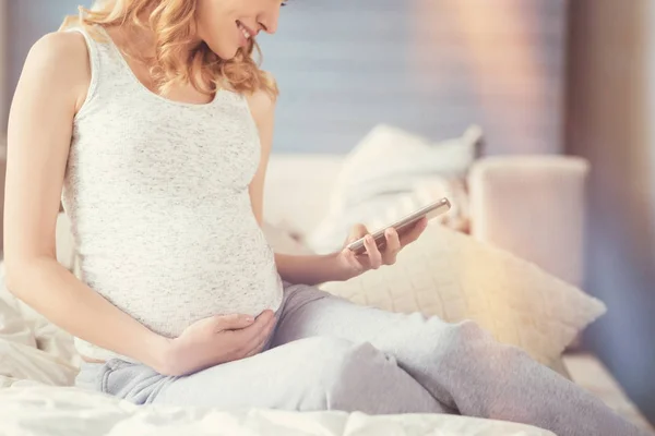 스마트폰을 사용 하 여 웃는 임신한 여자 — 스톡 사진