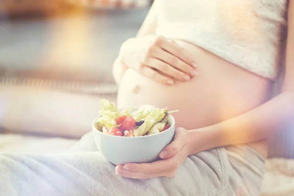 Agradable mujer embarazada sosteniendo ensalada griega — Foto de Stock