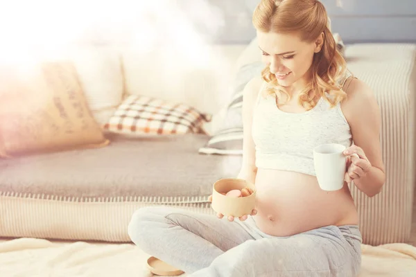 Mulher grávida positiva comer macaroons — Fotografia de Stock