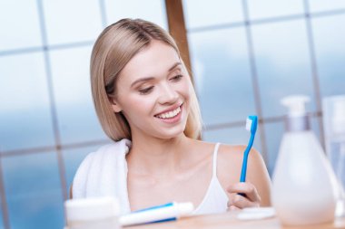 Diş fırçasını seyir ve gülümseyen neşeli kadın