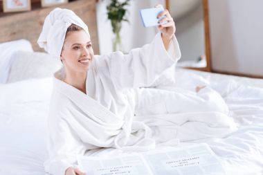 Hoş kadın yatakta selfie alarak bornoz