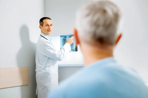 Wesoły dodatnie lekarz stojący w pobliżu obrazu X ray — Zdjęcie stockowe