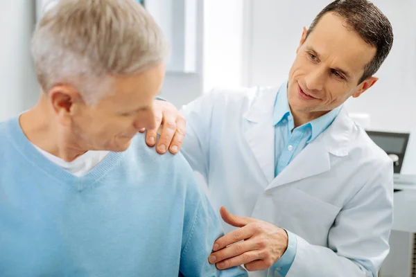 Cheerful positive doctor checking patients arm — Stock Photo, Image