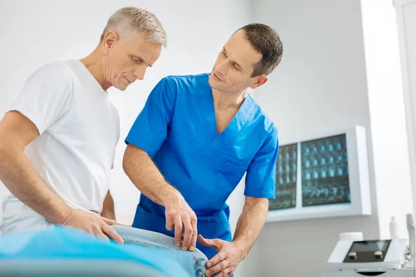 Médico hábil inteligente pressionando o dedo para o joelho — Fotografia de Stock