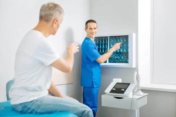 Веселый доктор, стоящий рядом с рентгеновскими снимками — стоковое фото