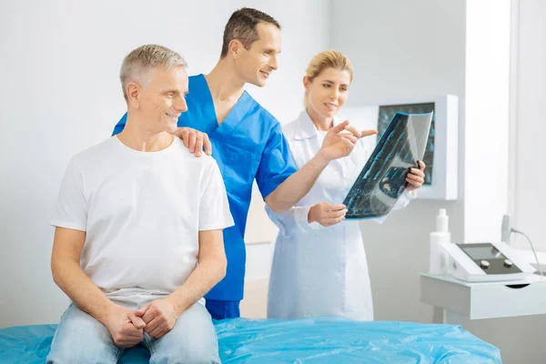 Восхитительный веселый терапевт, указывающий на рентгеновское изображение — стоковое фото