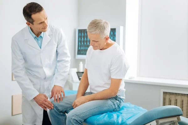 Positive professional doctor checking patients leg — Stock Photo, Image