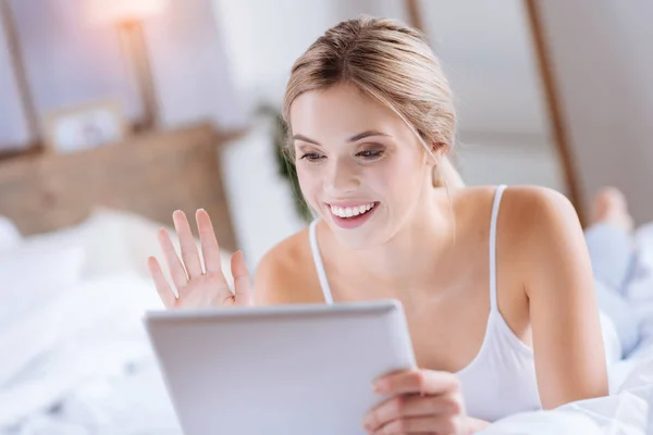 Cheerful blonde woman making a video call via tablet