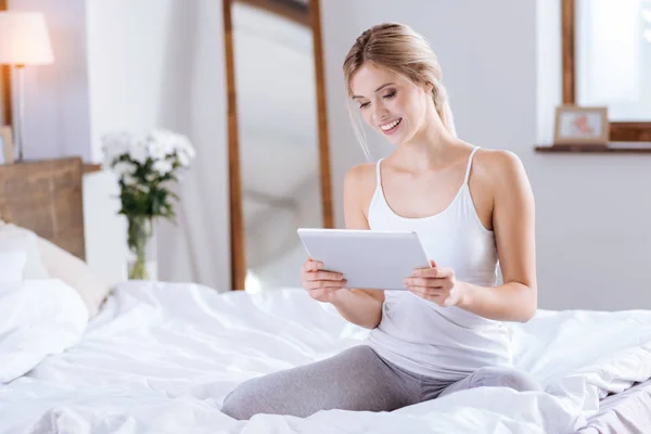 Mladá žena čte časopis z tabletu — Stock fotografie