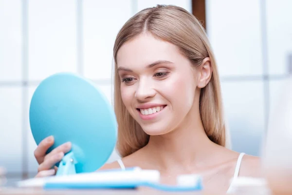 Mujer alegre mirando sus dientes en el espejo — Foto de Stock