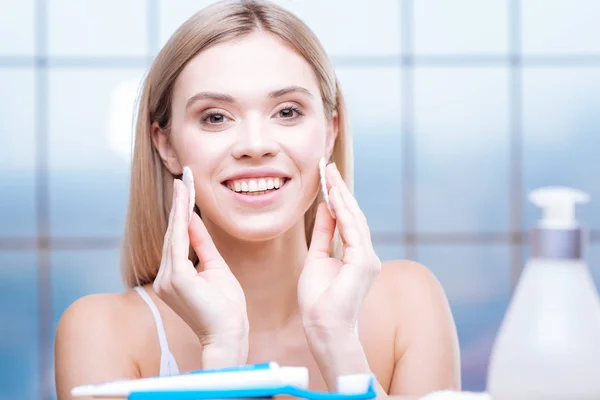 Glad ung kvinna att ta bort makeup från kinder — Stockfoto