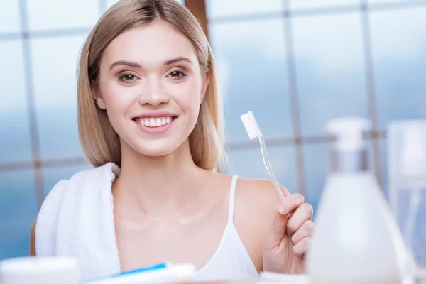 Mujer alegre mostrando un cepillo de dientes transparente y sonriente —  Fotos de Stock