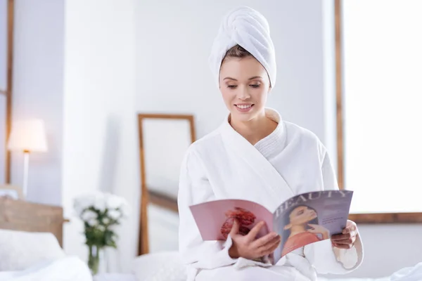 Mujer bonita en la revista de lectura de albornoz en el dormitorio — Foto de Stock