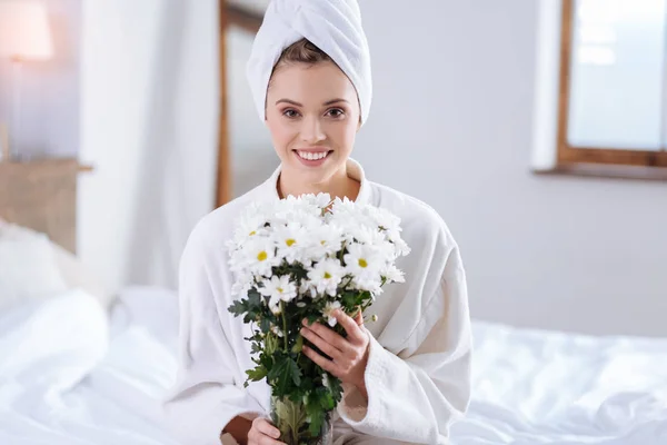 Gelukkige vrouw in badjas boeket van bloemen te houden — Stockfoto