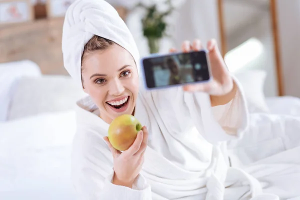 Upbeat woman taking selfie with apple after shower — Stockfoto