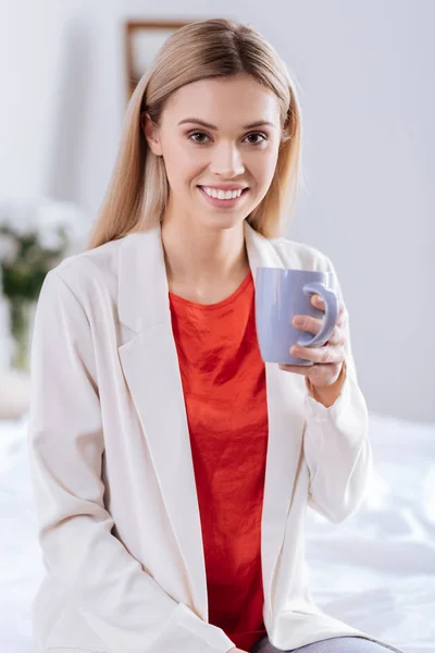 Mujer agradable en blusa roja sosteniendo taza de café — Foto de Stock