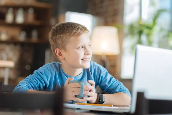 Positiver fröhlicher Junge mit einer Tasse in der Hand — Stockfoto