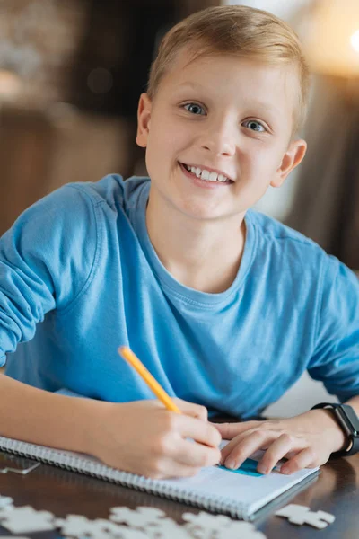 Feliz chico positivo haciendo una tarea escolar —  Fotos de Stock