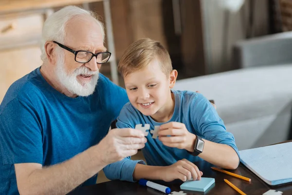 Happy elderly man collecting puzzles with his grandson — Stock Photo, Image