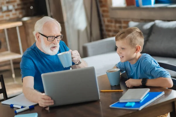 Hombre de edad positiva sosteniendo un ordenador portátil — Foto de Stock