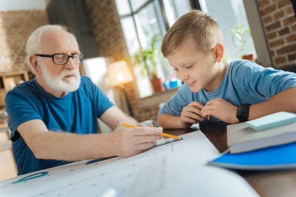 Nice happy boy looking at his grandfathers drawing — Stock Photo, Image