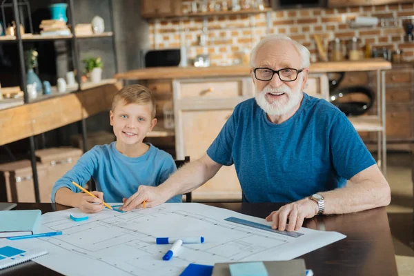 Положительный умный дедушка и внук делают чертеж — стоковое фото