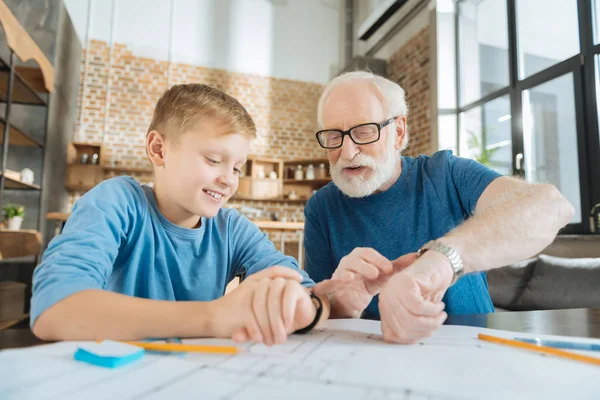 Positive cheerful grandfather and grandson looking at their watches — Stock Photo, Image