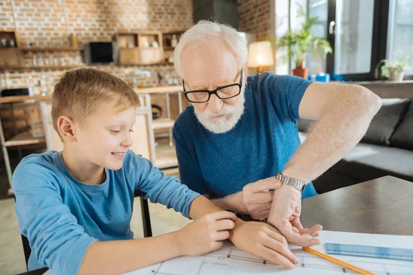 Happy nice grandfather and grandson comparing their watches — Stock Photo, Image