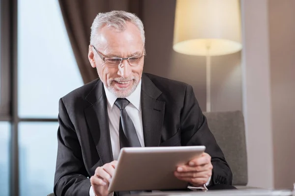 Jolly senior man die werkt met een tablet — Stockfoto