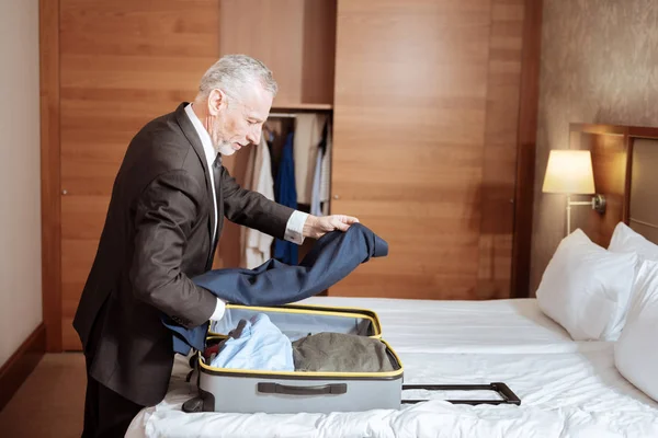Красивий старший чоловік кладе піджак у валізу — стокове фото