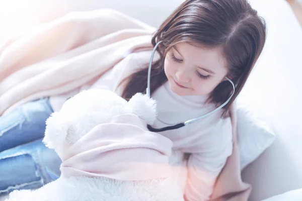 Visão superior da menina bonita enquanto sorri para seu urso de brinquedo — Fotografia de Stock