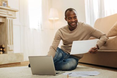 Mutlu adam çalışma kağıtları ile ve diz üstü