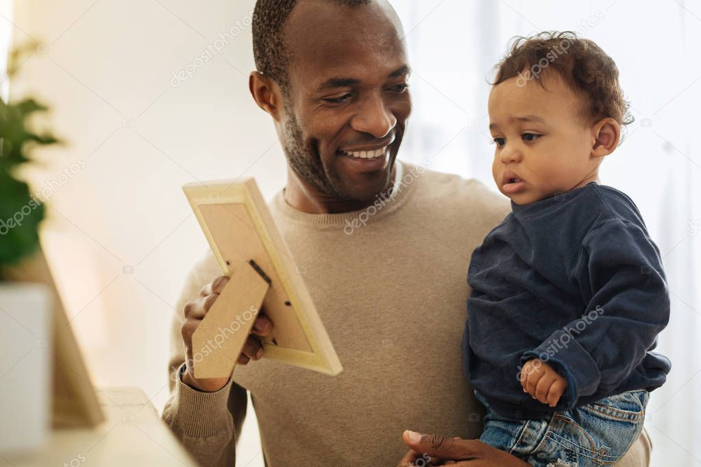 Cheerful daddy showing photos to his son