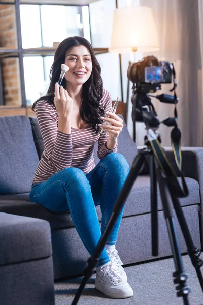 Mujer feliz alegre mostrando cómo utilizar el cepillo de maquillaje — Foto de Stock