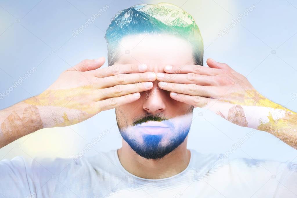 Portrait of a handsome bearded man covering his eyes