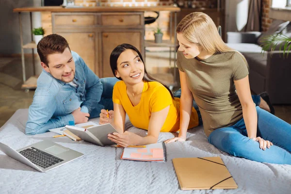 Drie vrolijke doordachte studenten uitvoeren van taak — Stockfoto