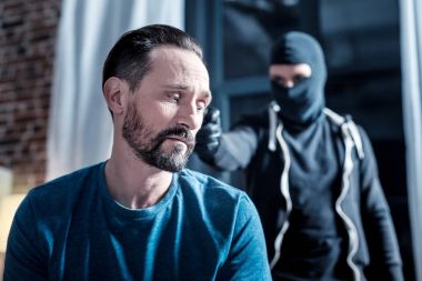 Korkmuş adam ve silah arkasında bir suçluyla