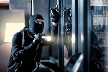 Masked burglar breaking into the house clipart