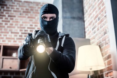 Irritated masked robber holding a torch clipart