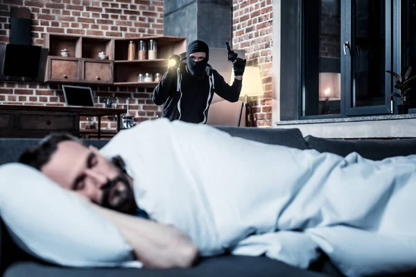 Maskierter Verbrecher mit Taschenlampe und Waffe — Stockfoto