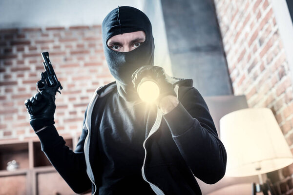 Enraged criminal holding a gun and a torch
