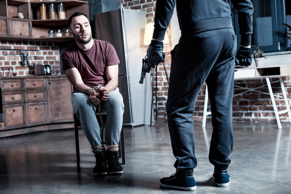 Intimidated man sitting in front of the killer