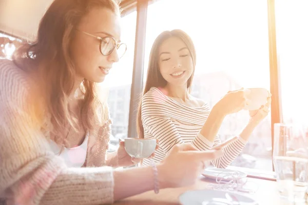 Glad tjej med vågigt hår som tittar på henne telefon — Stockfoto