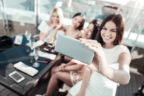 Jovens meninas felizes sentadas à mesa e fazendo foto . — Fotografia de Stock