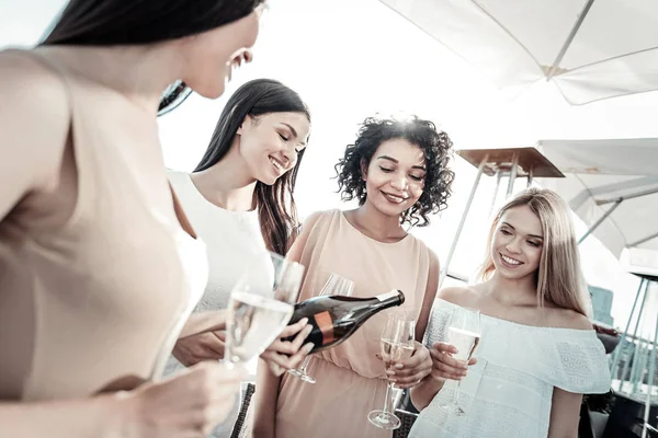 Amistosas chicas sonrientes divirtiéndose y bebiendo champán . — Foto de Stock